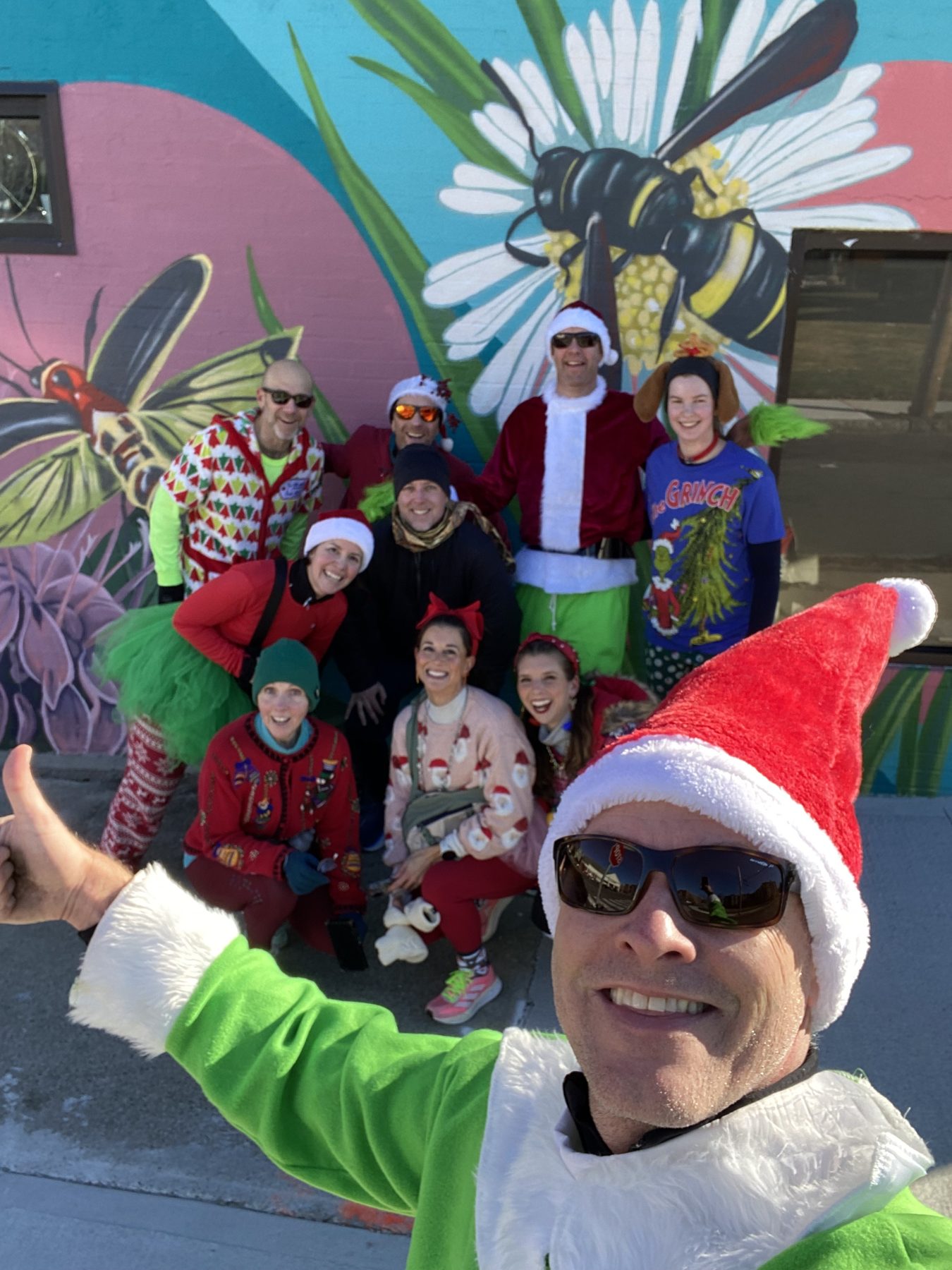 Grinch selfie with the crew in front of a mural